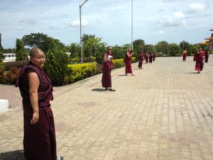 Grupa tybetańskich zakonnic stojących na zewnątrz.