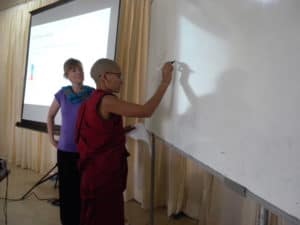 A Tibetan nun writing on a white board.