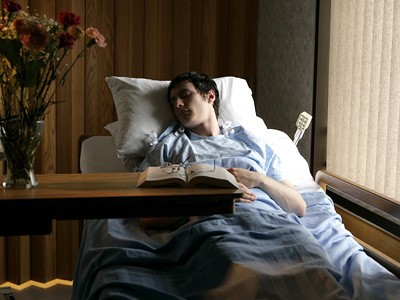 Young man lying in hospital bed.