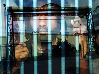 Inmate looking out from behind prison bars.