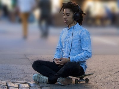 Młody mężczyzna siedzi na deskorolce, medytacji.