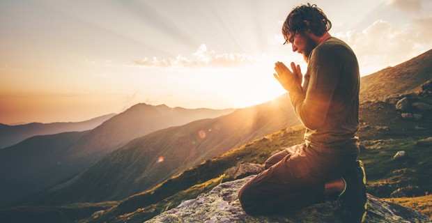 Young man praying at sunset.