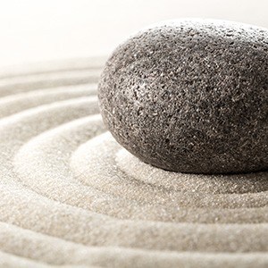 Gray stone and rings in sand of Zen rock garden.