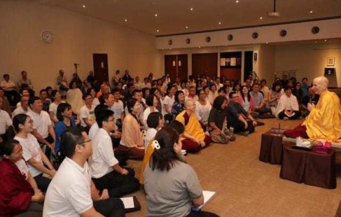 Venerable teaching in front of a large crowd at Nalanda Buddhist Centre.