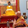 Venerable teaching at Jewel Heart Nigmegen, smiling, in front of a large Buddha.
