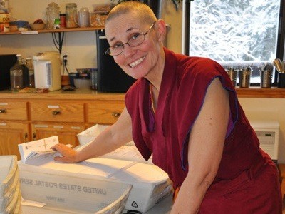 Venerable Chonyi smiling while sorthing through bins of mail.