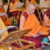 Venerable Chodron and other Abbey monastics sitting on meditation cushions and reading a text.