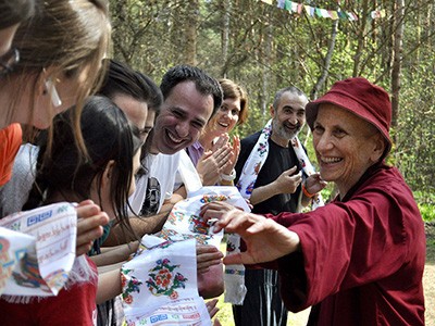 Venerable Chodron smiling and reaching for a khata Russian students are offering.