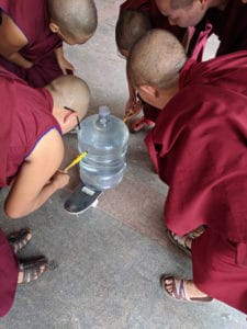 Tibetské jeptišky klečí a provádějí experiment.