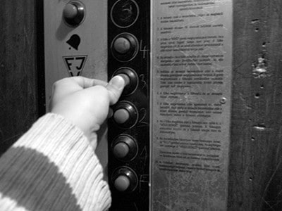Person's finger pushing a button in an elevator.