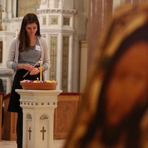 Woman lighting a candle during Catholic mass.