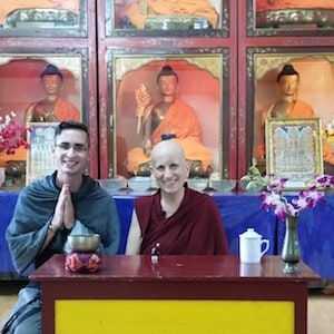 Venerable and student smiling in front of Buddha statues.