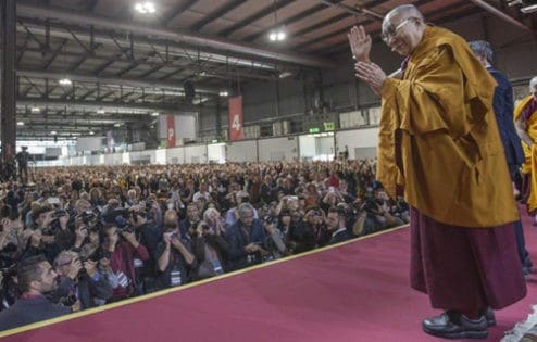 Jego Świątobliwość Dalajlama machający do wielkiego tłumu na nauczaniu.