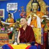 Ven. Chodron smiling while teaching in front of a large Buddha statue.