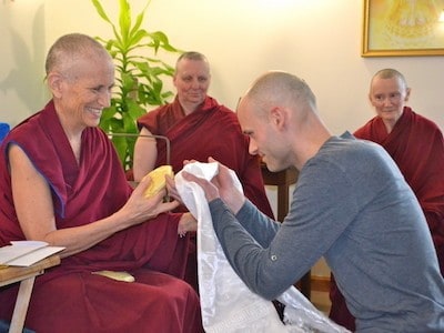 Stephen kneeling in front of Venerable Chodron and offeirng a khata.