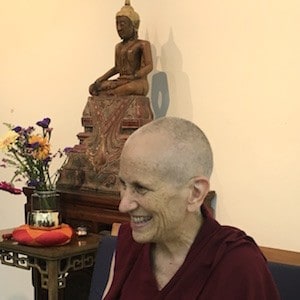 Venerable smiling while teaching in front of a Buddha statue.