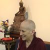 Venerable smiling while teaching in front of a Buddha statue.
