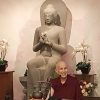 Venerable smiling in front of large Buddha statue.