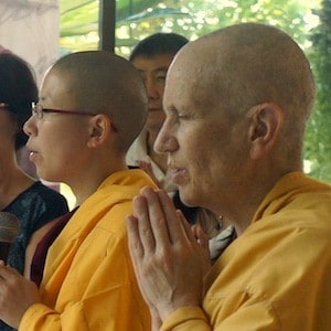 Venerable chanting with eyes closed and palms together.