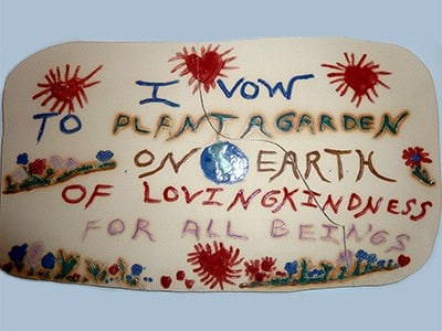 Tabliczka z napisem: „Ślubuję zasadzić ogród na ziemi pełnej miłości dobroci dla wszystkich istot”.