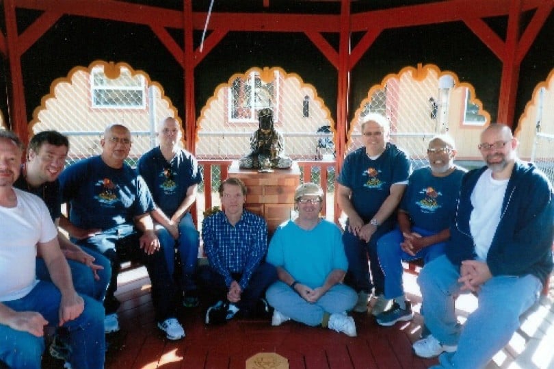 Group of inmates sitting together in front of a Buddha statue.