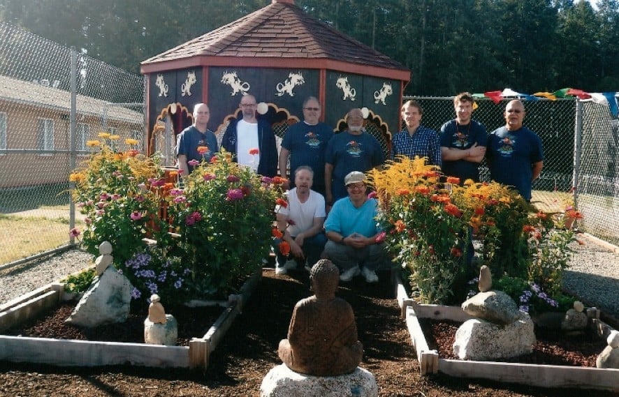 Group of inmates sitting under pagoda, in front of a Buddha statue.