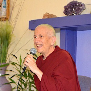Venerable holding a microphone and smiling while teaching at Gardenia Center.