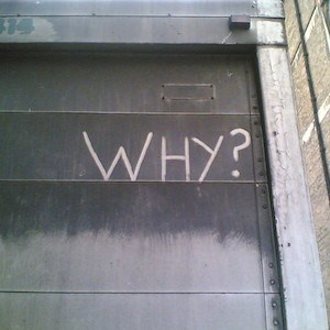 Słowo „Dlaczego?” napisane na metalowych drzwiach przesuwnych.