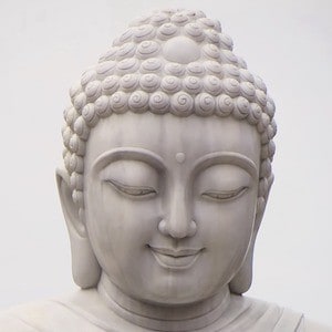 Closeup of the statue of a smiling Buddha's face.