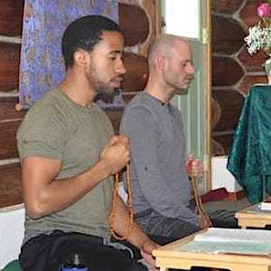Dwóch młodych mężczyzn siedzących obok siebie i medytujących.