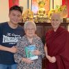 Kenryuu with his arm around his mother, both smiling and standing with Venerable Chodron.