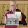 Venerable Chonyi holding up a book before leading a meditation.