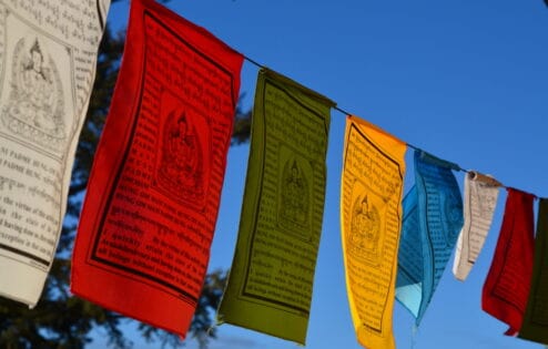 Colorful prayer flags against a clear blue sky.
