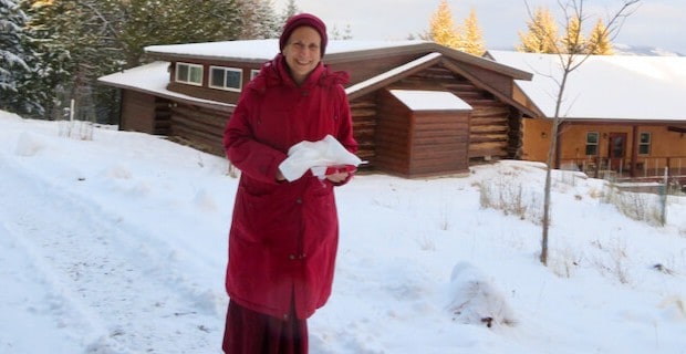 Venerable Chodron smiling while walking down a snowy path at the Abbey.