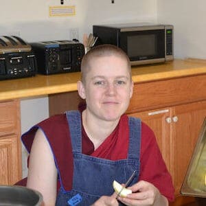 Venerable Lamsel smiling while cutting an apple.