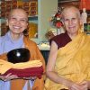 Venerable Pende standing next to Venerable Chodron, holding her robes and smiling.