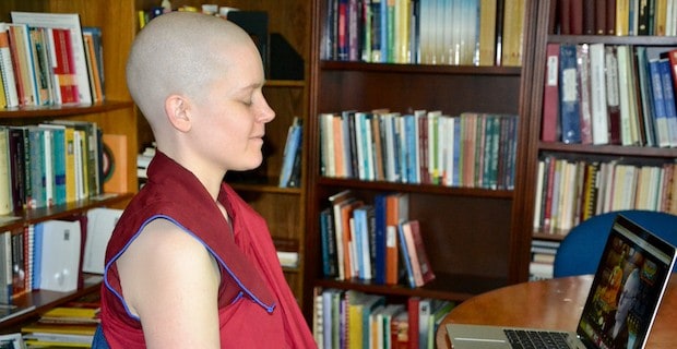 Nun smiling while meditating in a library.