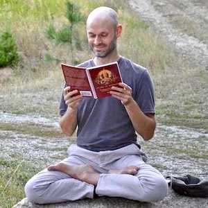 Stephen siedzący na zewnątrz w pozycji medytacyjnej, czytający księgę Dharmy.