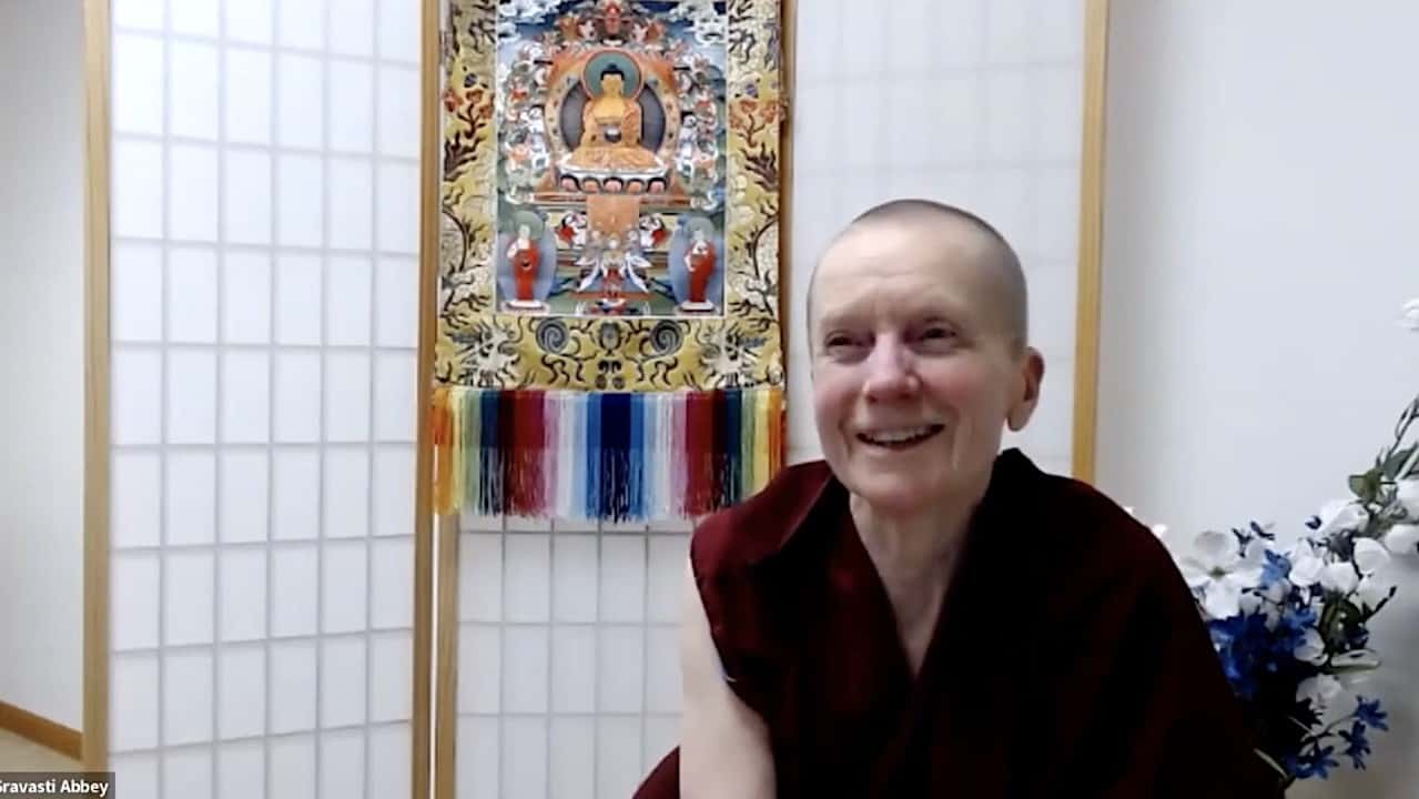 Venerable Sangye Khadro sitting in front of a thangka, smiling.