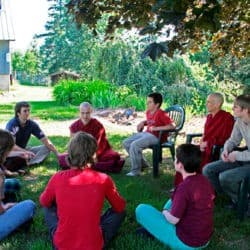 Czcigodni uczestnicy Tygodnia Chodron i Tygodnia Młodych Siedzą w kręgu, aby dyskutować o Dharmie w ogrodzie opactwa Sravasti.