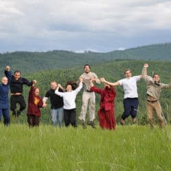 Venerable Chodron and Young Adult Week participants join hands and jump in the air in the upper meadow.
