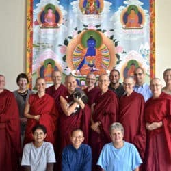 Uczestnicy Odkrywania życia monastycznego robią grupowe zdjęcie przed obrazem ośmiu Buddów Medycyny.