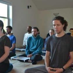 Uczestnicy Tygodnia Młodych Dorosłych siedzą w medytacji.