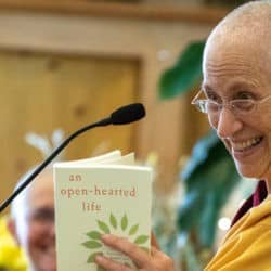 Venerable Chodron smiles while reading from a copy of "An Open-Hearted Life."
