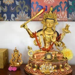 Bronze statue of Manjushri bodhisattva on an altar.