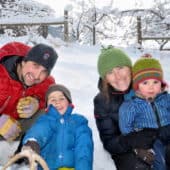 Rodzice i ich dwoje małych dzieci bawią się na śniegu w opactwie Sravasti.