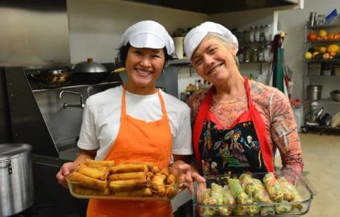 Two women offer hand-made spring rolls.