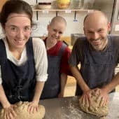 Young people knead bread together in the Sravasti Abbey kitchen.