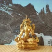 Golden Tara statue in front of a card showing a river and mountains.