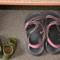A pair of baby sandals next to a pair of adult sandals.